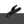 A black welding ground clip with a textured handle and copper-colored contact tips, shown against a split white and dark gray background.