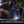 A person wearing a dark welding helmet, work gloves, and a dark hoodie is actively welding metal in a workshop, with bright sparks flying. A text overlay at the bottom reads, 'Built for People Who Fix Things Themselves'.